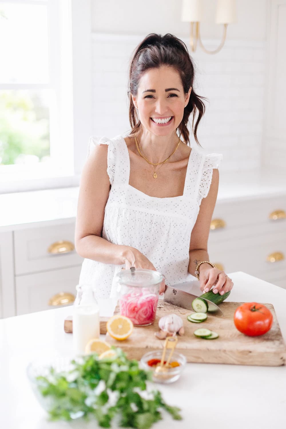 Tori Wesszer smiling while slicing cucumber in her kitchen