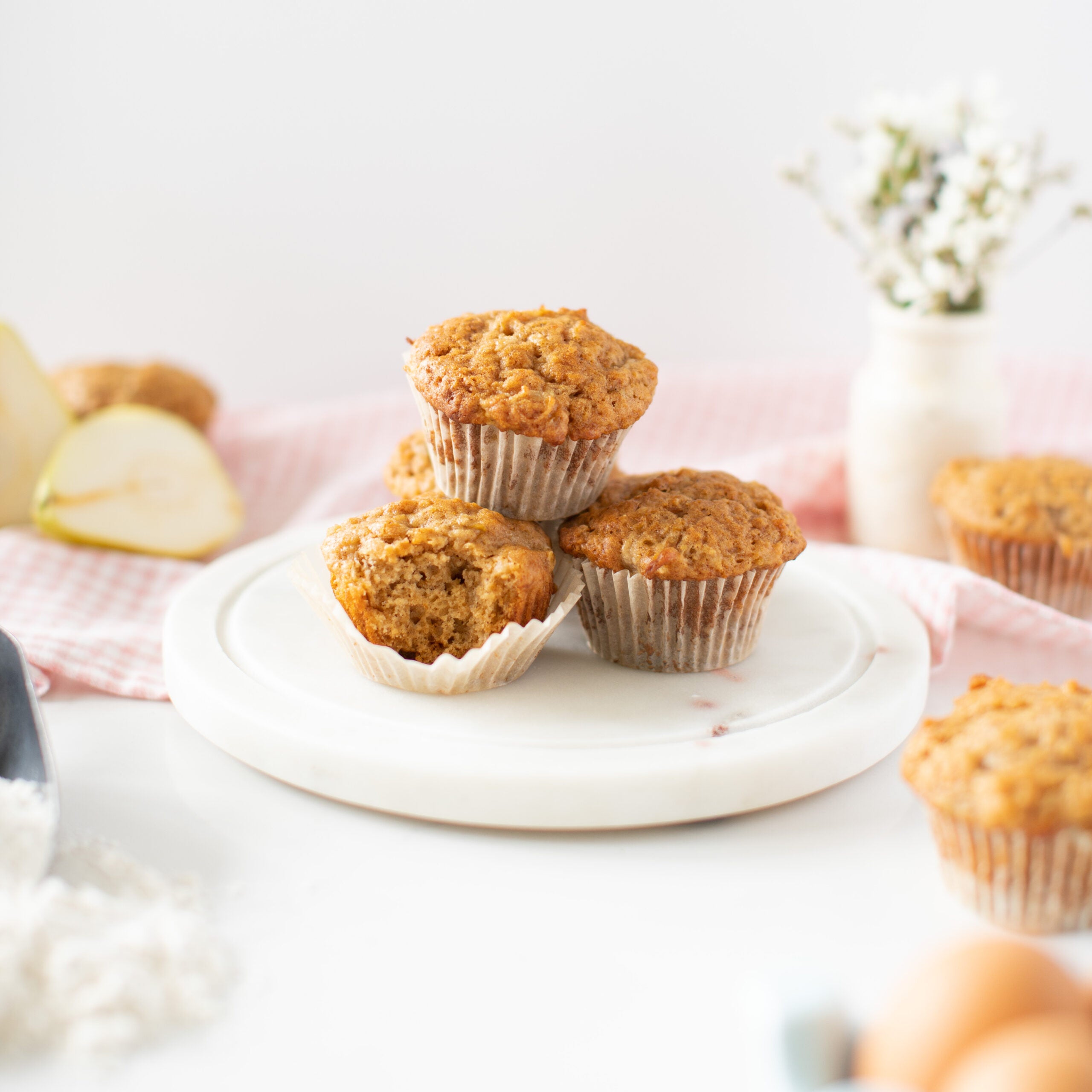 three pear yogurt muffins stacked together with a bite taken out of them