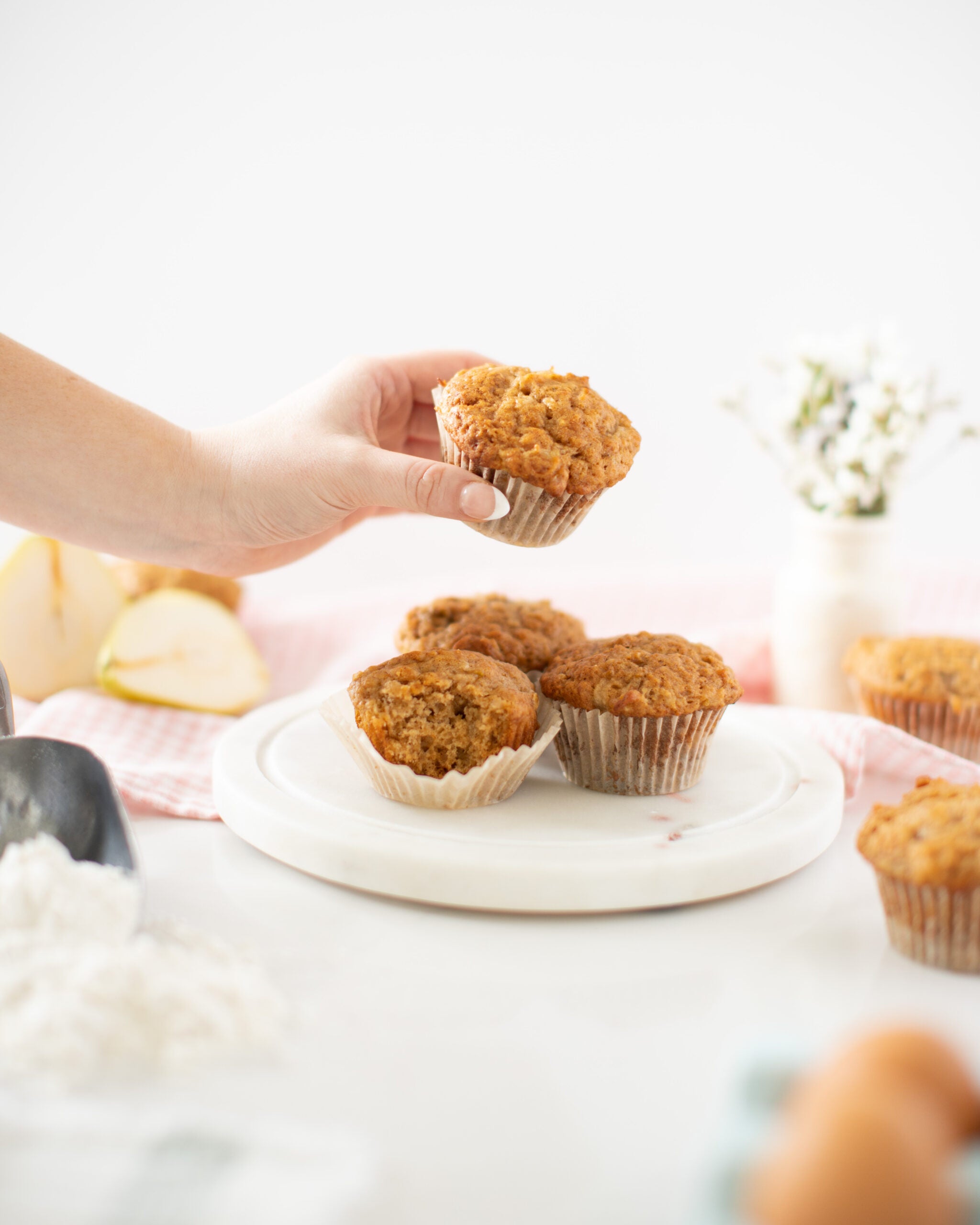 stack of pear yogurt muffins with ladies hand picking one up to eat