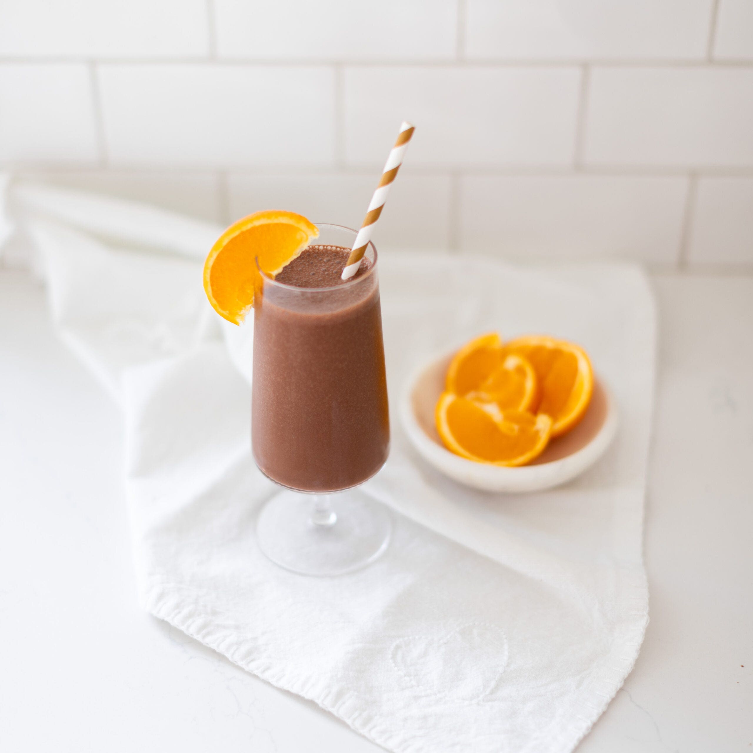 chocolate orange smoothie in a glass topped with a fresh orange slice