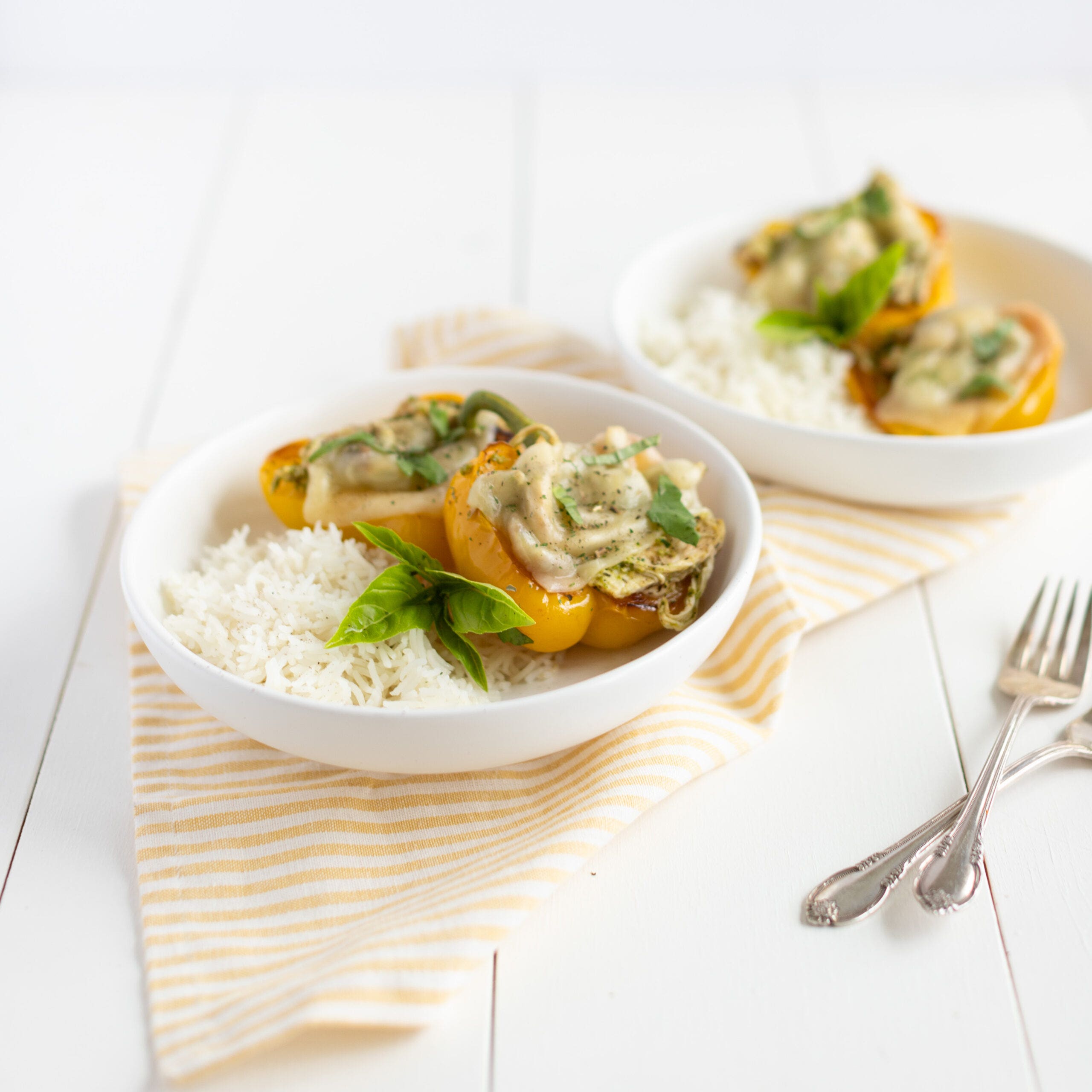 bell peppers stuffed with pesto chicken and topped with mozzarella cheese, served with rice