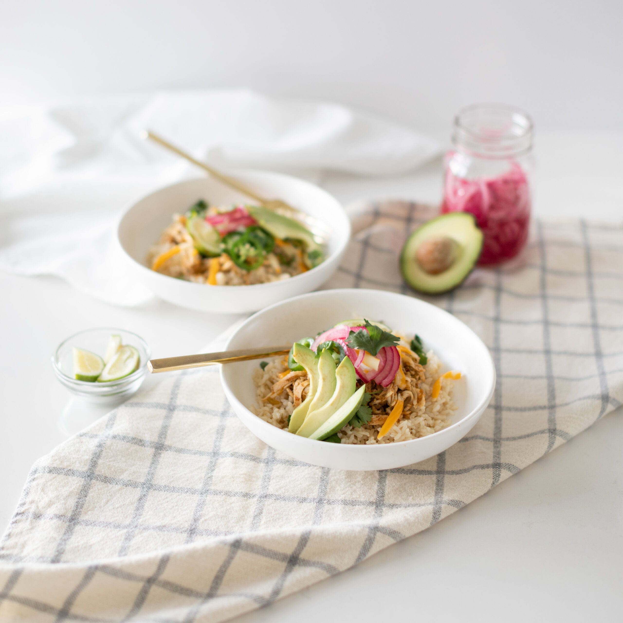 brown rice and slow cooked chicken served with avocado, pickled red onions, cilantro, and sour cream on top