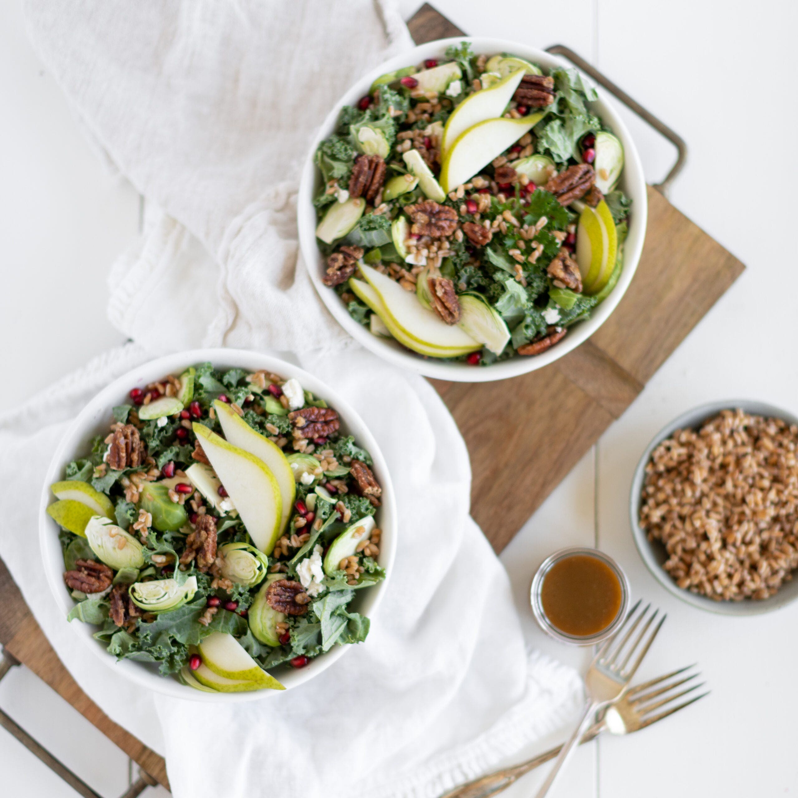 delicious salad containing farro, brussel sprouts, pears, pecans, and feta with dressing on the side