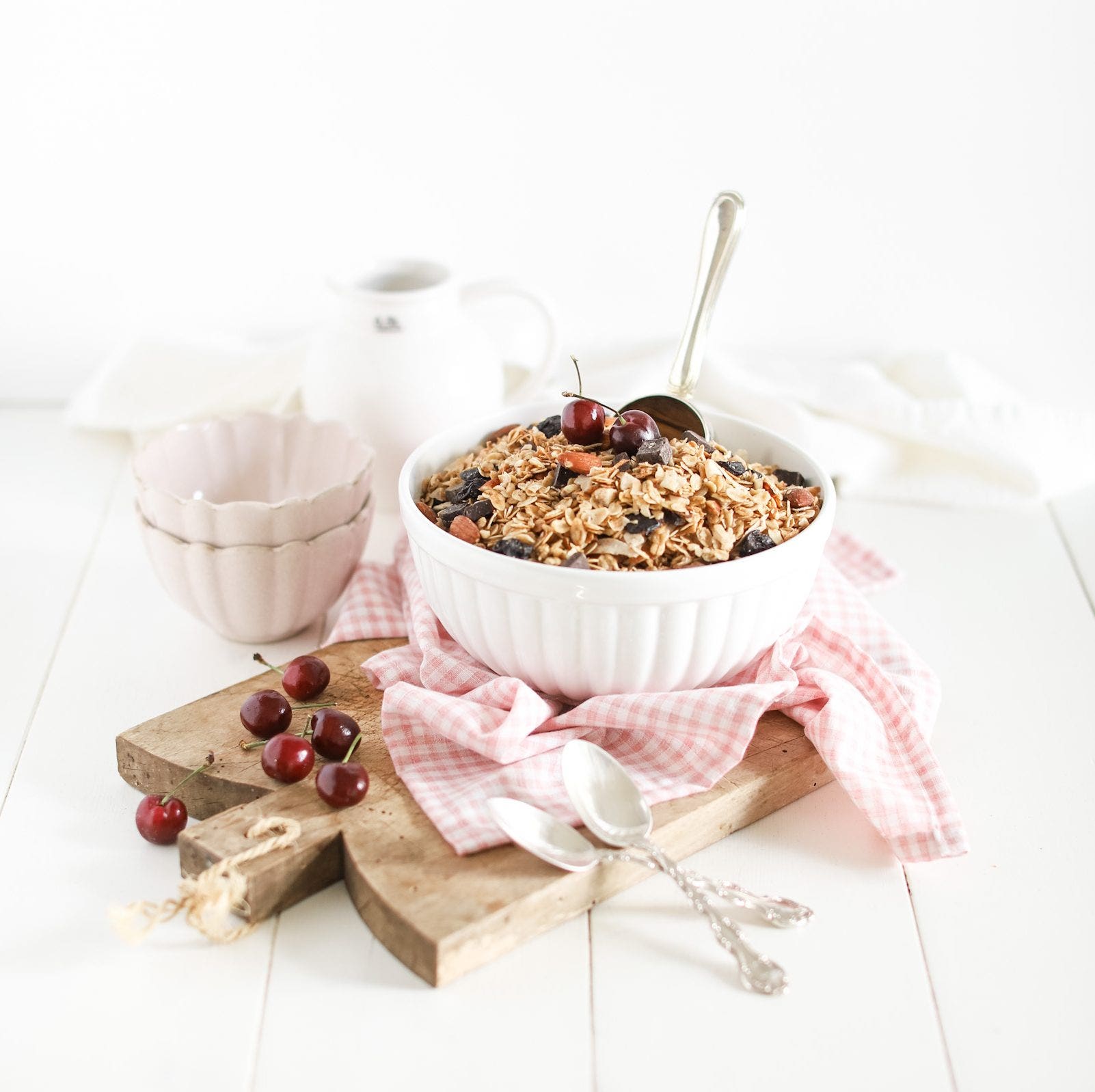 granola in a bowl layered with dark chocolate, dried cherries, shredded coconut with cherries as a garnish