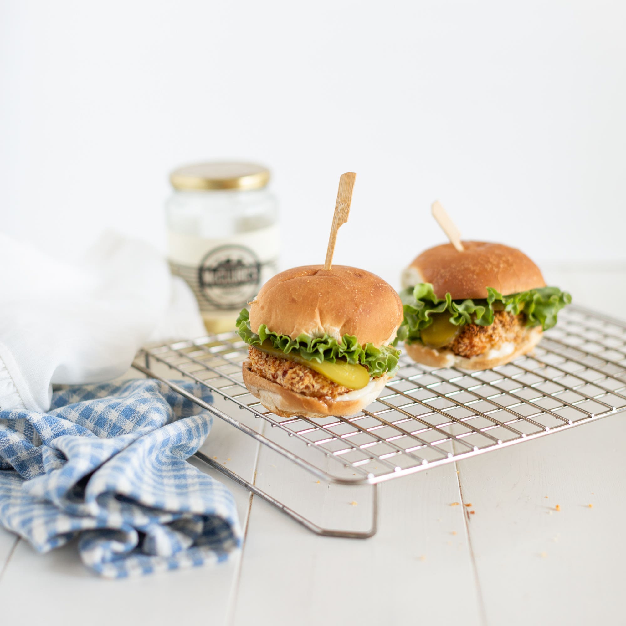 two crispy chicken sandwiches with a jar of pickles