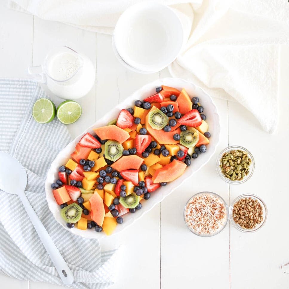 A big serving bowl of Coconut Lime Fruit Salad made of blueberries, strawberries, mango, papaya, kiwi, lime juice and toasted coconut. 