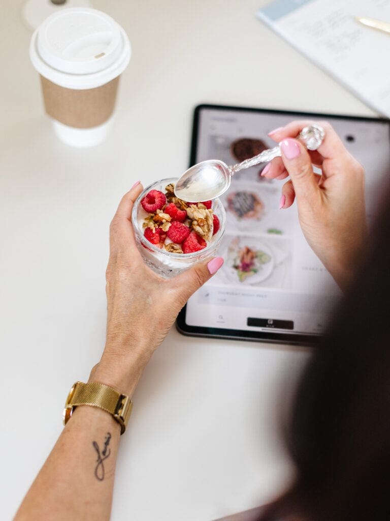 Women sitting at desk eating a yogurt parfait with berries and granola