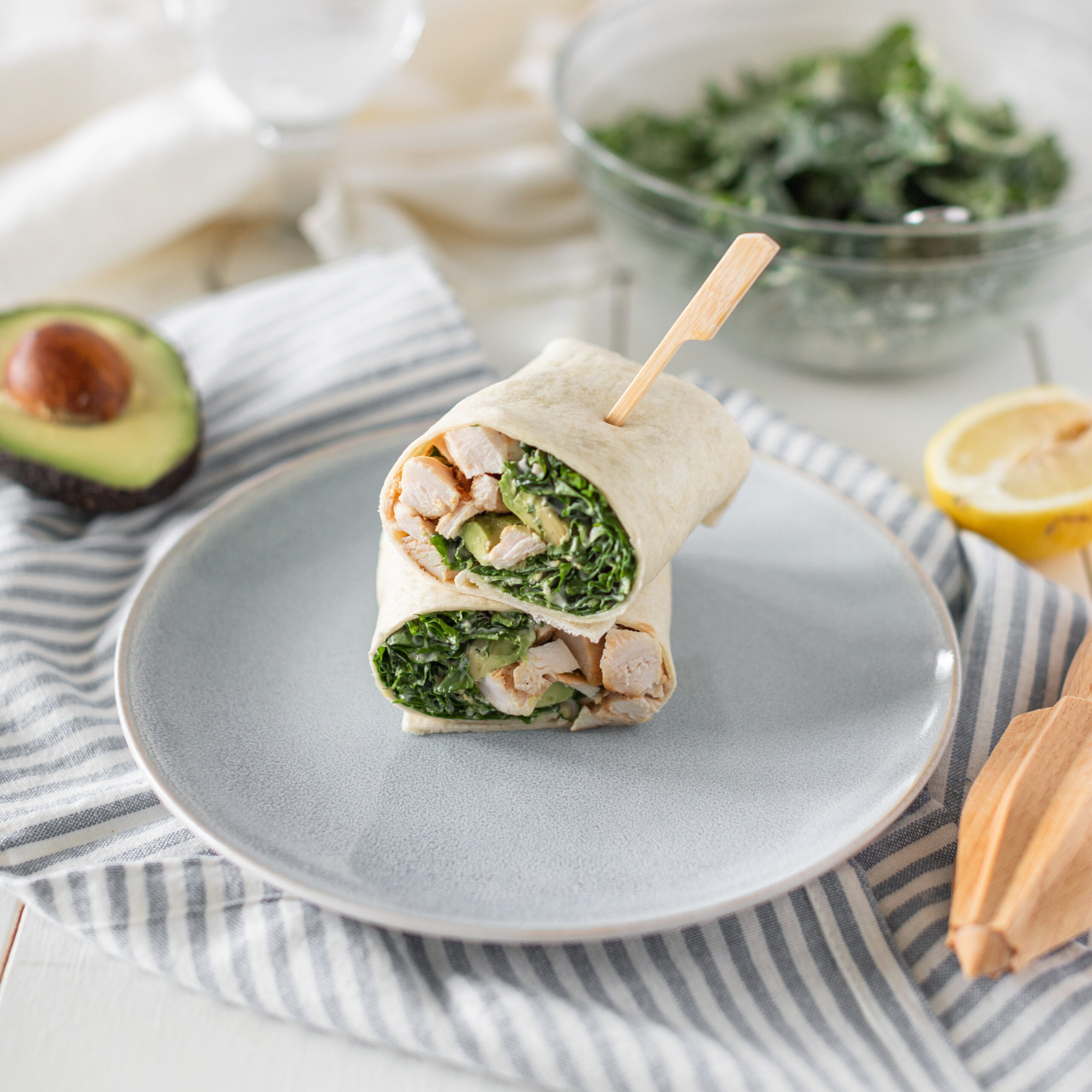 Tortilla wrap cut in half on a plate showing kale tofu and avocado inside