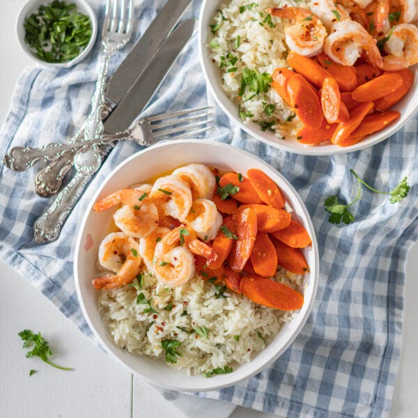 bowls of shrimp and carrots on top of rice pilaf