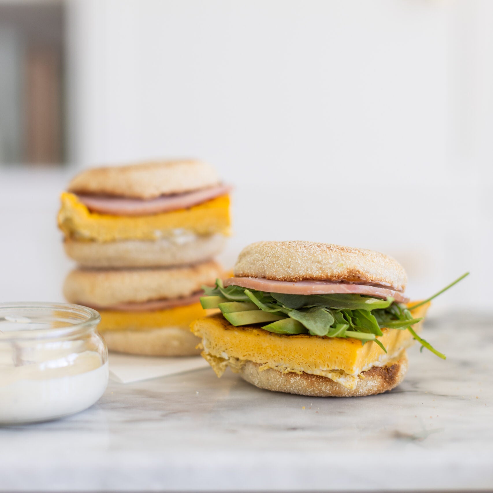 breakfast sandwich on an english muffin with egg, arugula and ham